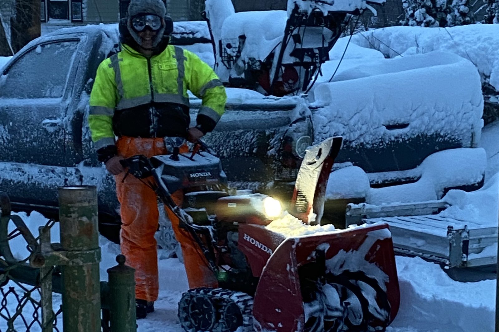 Handyman James clearing snow before dawn with a tracked Honda snowblower during a Massachusetts storm